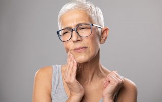 Woman with jaw pain after getting dental implants (4 Facts About the Dental Implant Recovery Process)