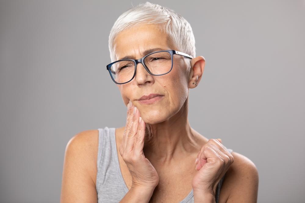 Woman with jaw pain after getting dental implants (4 Facts About the Dental Implant Recovery Process)